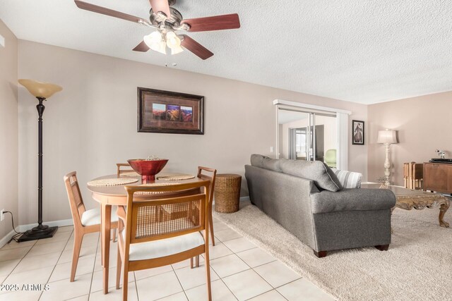 dining area with light tile patterned flooring, ceiling fan, a textured ceiling, and baseboards