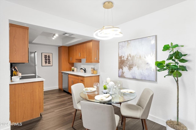 dining space with dark hardwood / wood-style flooring, sink, and a raised ceiling