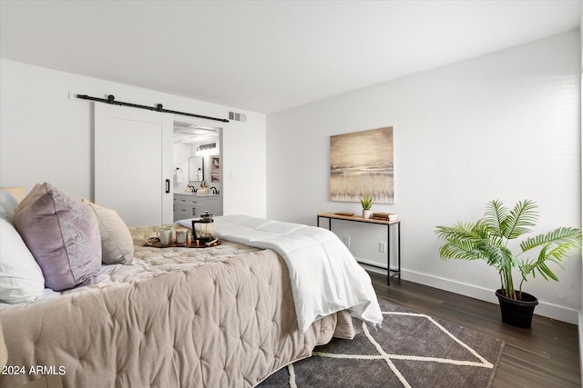 bedroom with a barn door and dark hardwood / wood-style floors