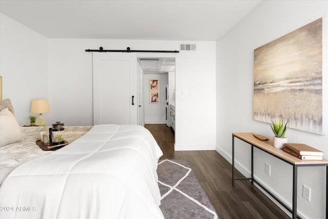 bedroom with a barn door and dark hardwood / wood-style flooring