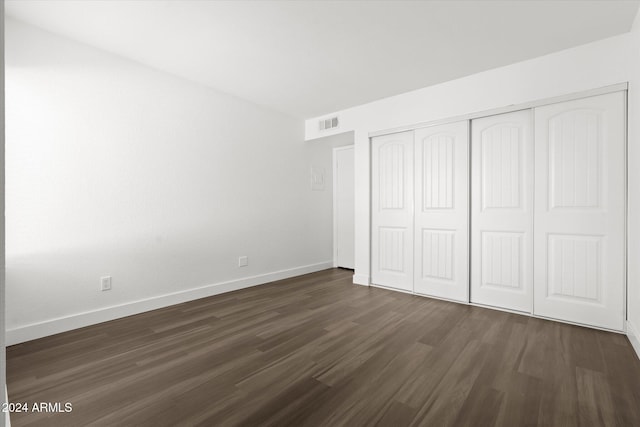 unfurnished bedroom featuring dark hardwood / wood-style flooring and a closet