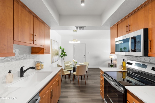 kitchen with stainless steel appliances, pendant lighting, backsplash, and dark hardwood / wood-style flooring