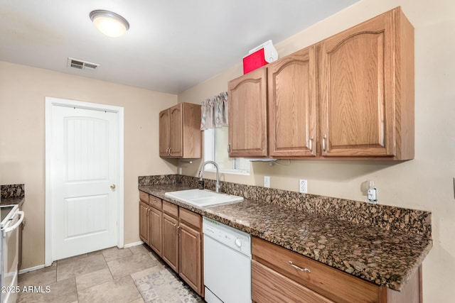 kitchen featuring sink, white appliances, and dark stone counters