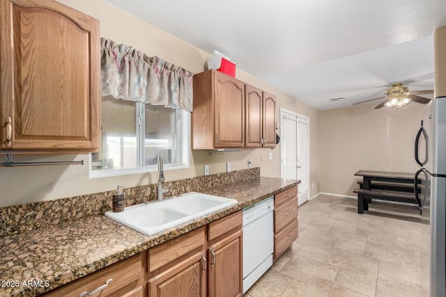 kitchen featuring sink, stainless steel fridge, ceiling fan, white dishwasher, and stone countertops