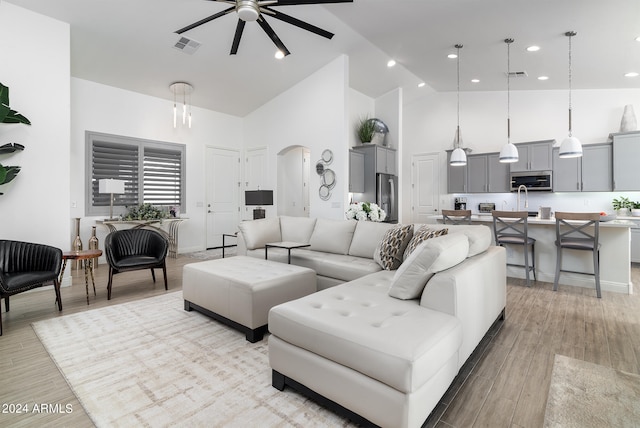 living room with high vaulted ceiling, light wood-type flooring, and ceiling fan