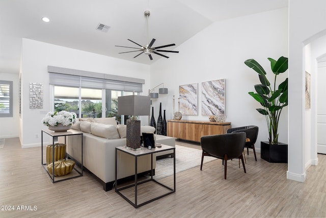 living room with ceiling fan, light wood-type flooring, and vaulted ceiling