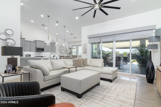 living room with high vaulted ceiling, ceiling fan, and light hardwood / wood-style flooring