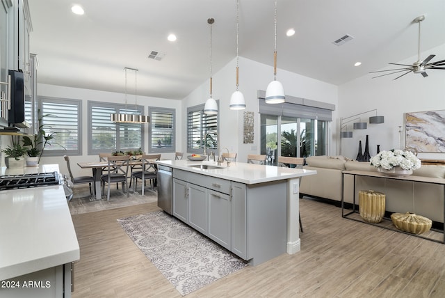 kitchen featuring an island with sink, gray cabinets, hanging light fixtures, and a healthy amount of sunlight