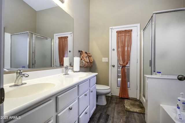 bathroom featuring wood-type flooring, vanity, toilet, and walk in shower