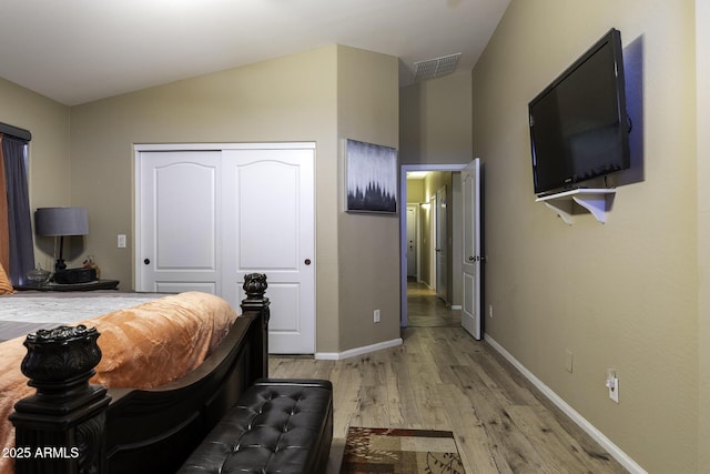 bedroom with a closet, lofted ceiling, and light hardwood / wood-style flooring