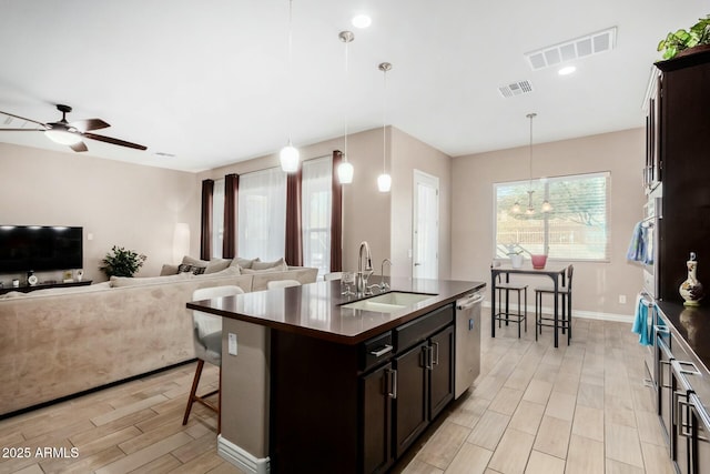 kitchen with hanging light fixtures, stainless steel appliances, a kitchen island with sink, and sink