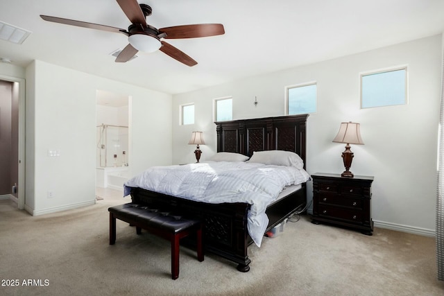 bedroom with ceiling fan, light colored carpet, and ensuite bath