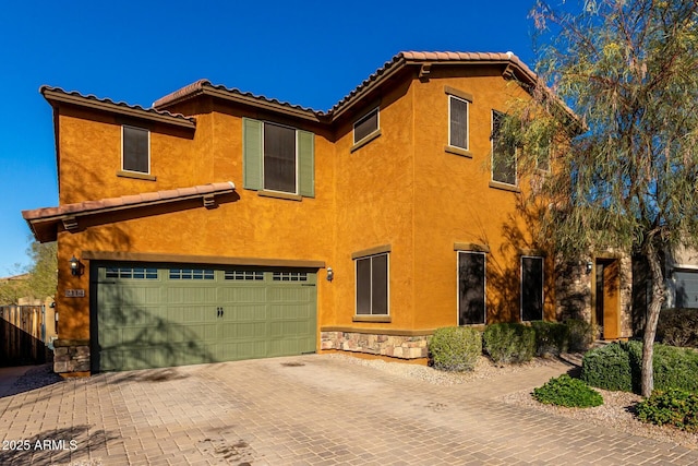 view of property exterior featuring stone siding, decorative driveway, an attached garage, and stucco siding