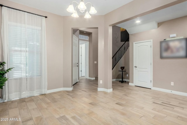 empty room with light wood-style floors, stairway, baseboards, and an inviting chandelier