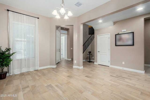 spare room with a chandelier and light wood-type flooring