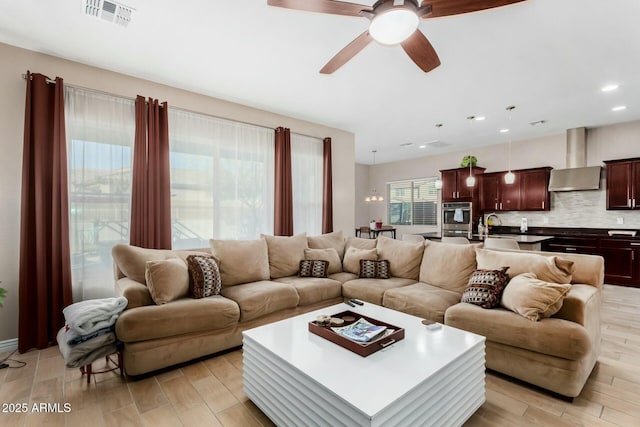 living room featuring sink, light hardwood / wood-style floors, and ceiling fan with notable chandelier