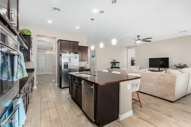 kitchen featuring ceiling fan, sink, decorative light fixtures, a center island with sink, and appliances with stainless steel finishes