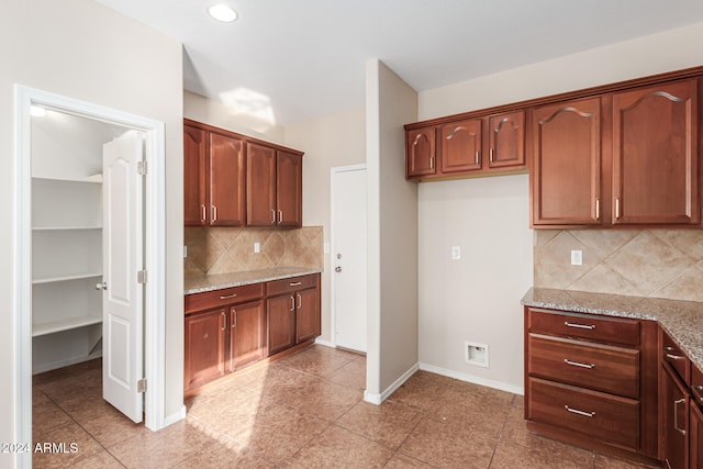 kitchen with decorative backsplash, light tile patterned floors, and light stone counters