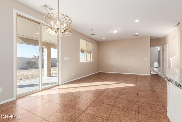 tiled spare room featuring a chandelier