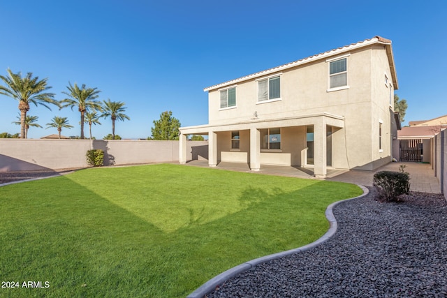 rear view of property featuring a lawn and a patio area