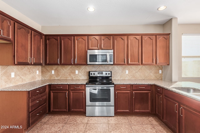 kitchen with tasteful backsplash, light stone countertops, light tile patterned floors, and stainless steel appliances