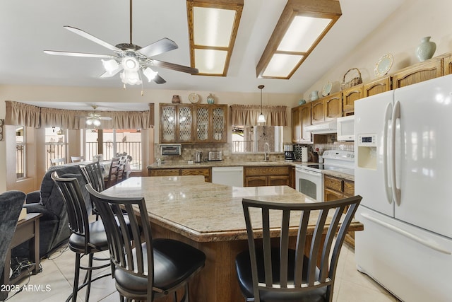 kitchen with light tile patterned flooring, white appliances, hanging light fixtures, brown cabinets, and glass insert cabinets