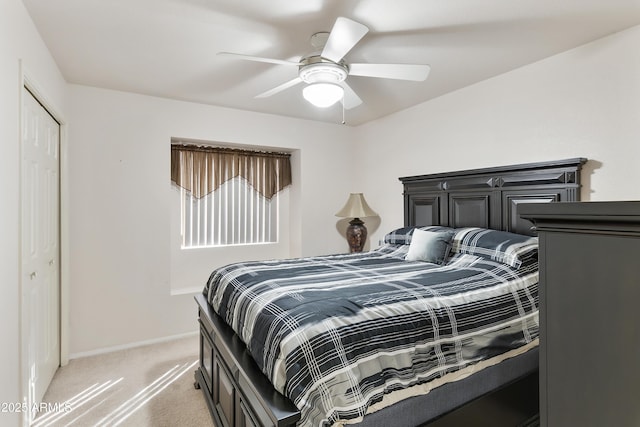 bedroom with a ceiling fan, a closet, light colored carpet, and baseboards