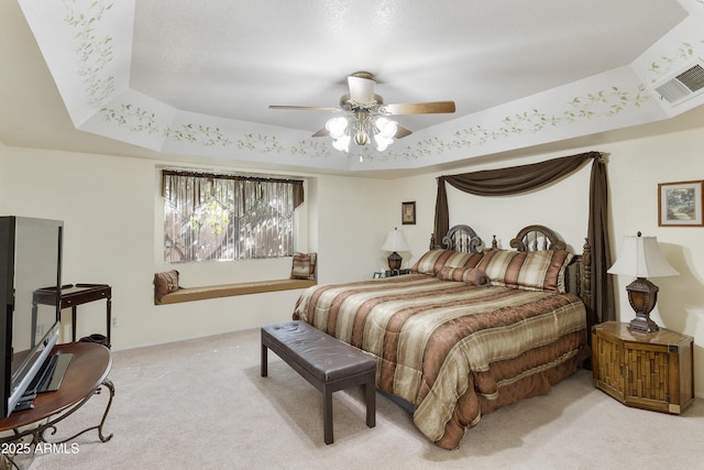 bedroom featuring a raised ceiling, light colored carpet, visible vents, ceiling fan, and baseboards
