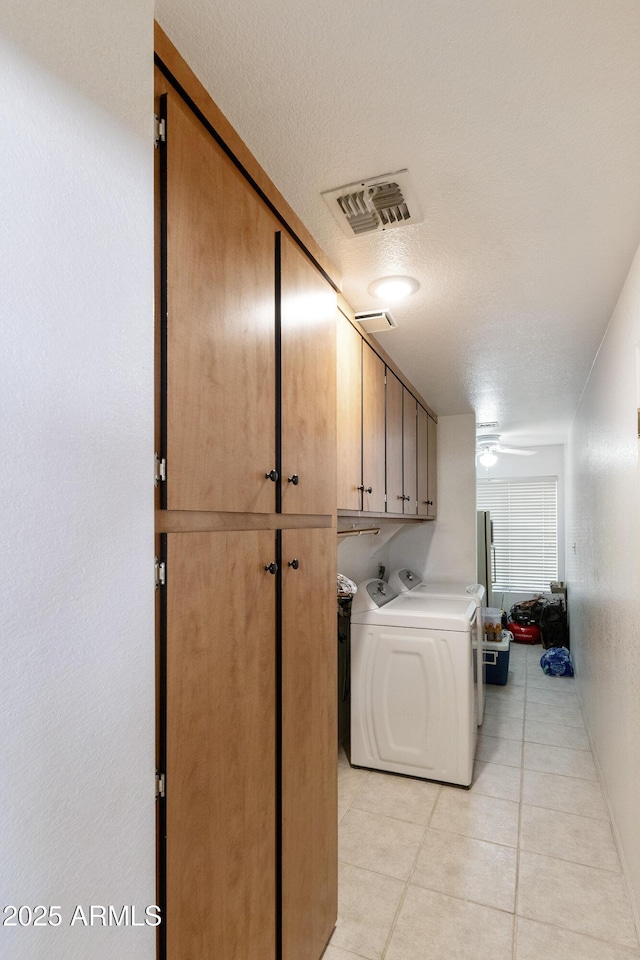 clothes washing area with cabinet space, light tile patterned floors, visible vents, a ceiling fan, and separate washer and dryer