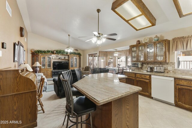 kitchen with brown cabinetry, white dishwasher, open floor plan, and a wealth of natural light