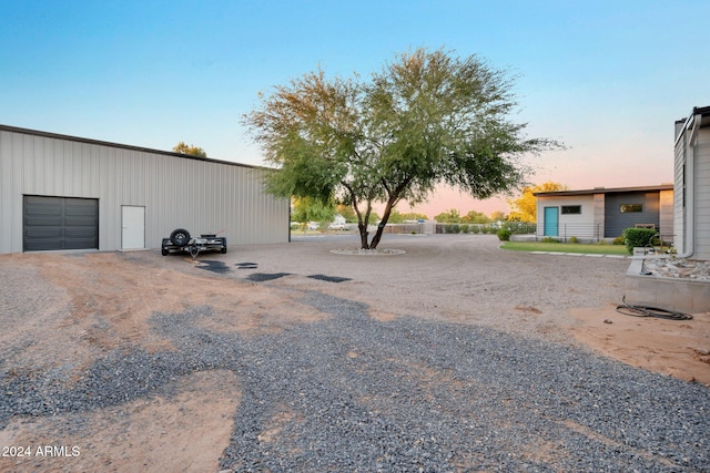 yard at dusk with a garage and an outdoor structure