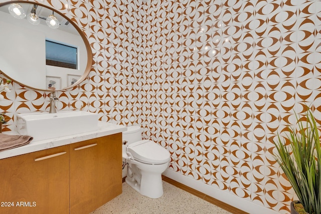 bathroom with toilet, vanity, baseboards, and speckled floor