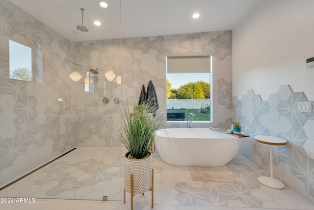 bathroom featuring walk in shower, a freestanding tub, tile walls, and recessed lighting