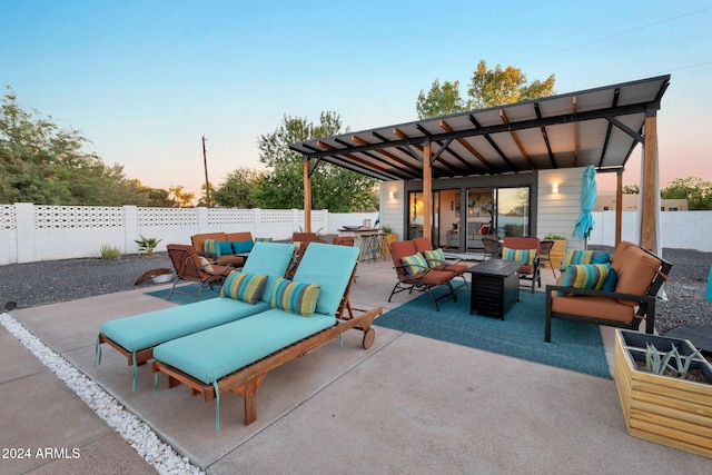 patio terrace at dusk with a fenced backyard, outdoor lounge area, and outdoor dining space