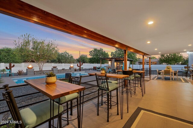 patio terrace at dusk with a fenced in pool, outdoor dining area, a fenced backyard, and a pergola