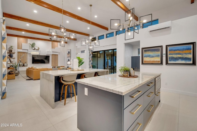 kitchen with a spacious island, gray cabinets, hanging light fixtures, a wall mounted air conditioner, and beamed ceiling