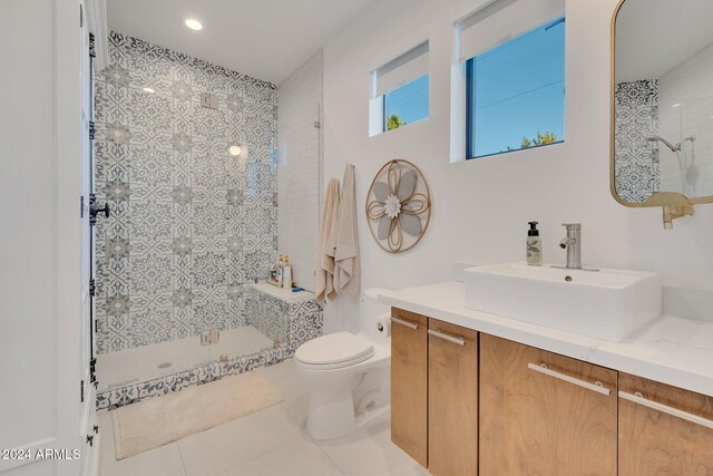 full bath featuring a tile shower, vanity, toilet, and tile patterned floors