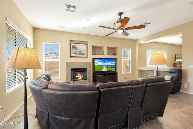 living room featuring ceiling fan, built in features, a healthy amount of sunlight, and a fireplace