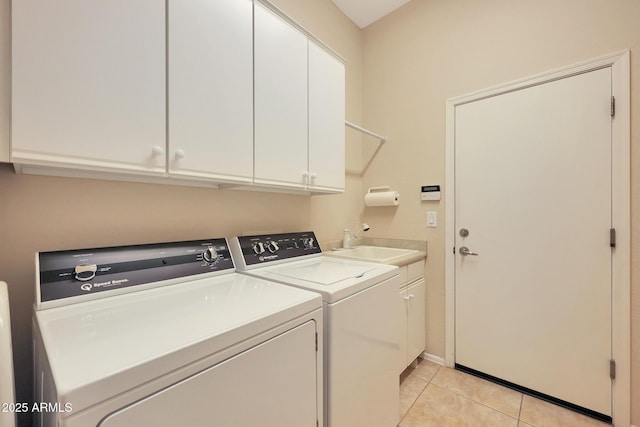 laundry area featuring washer and clothes dryer, sink, light tile patterned floors, and cabinets