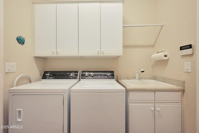 laundry area with washing machine and dryer, cabinets, and sink