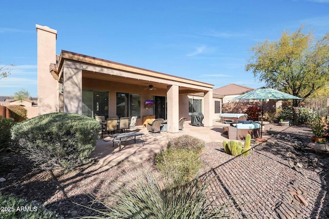 back of property featuring ceiling fan, a hot tub, and a patio