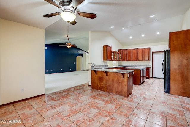 kitchen featuring light tile floors, ceiling fan, sink, a center island, and black refrigerator