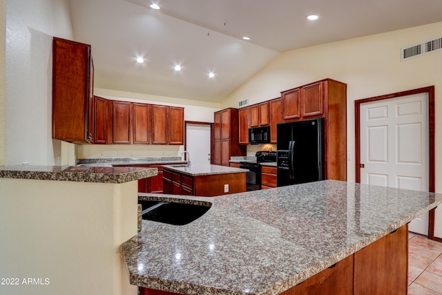 kitchen with light stone countertops, kitchen peninsula, a center island, and black appliances