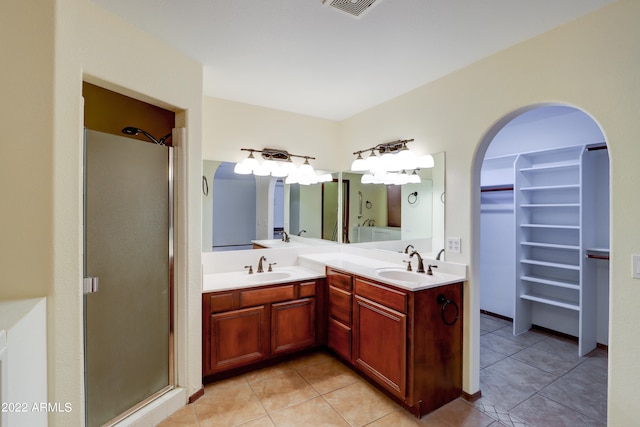 bathroom featuring a shower with door, large vanity, tile floors, and double sink