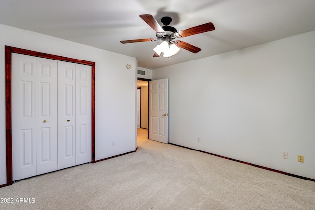 unfurnished bedroom with light colored carpet, ceiling fan, and a closet