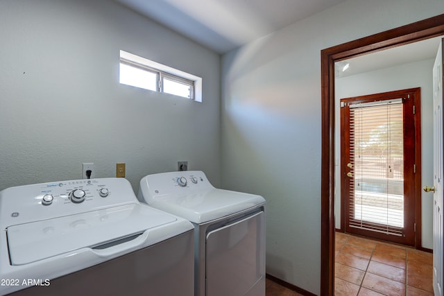 laundry area with hookup for an electric dryer, washing machine and dryer, and light tile floors