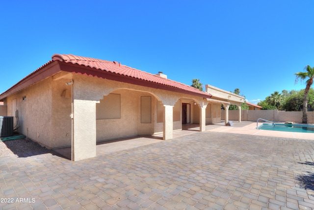 rear view of house with a patio, central air condition unit, and a fenced in pool