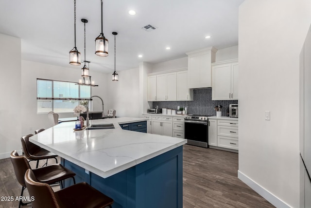 kitchen featuring pendant lighting, a breakfast bar, sink, stainless steel range, and white cabinetry