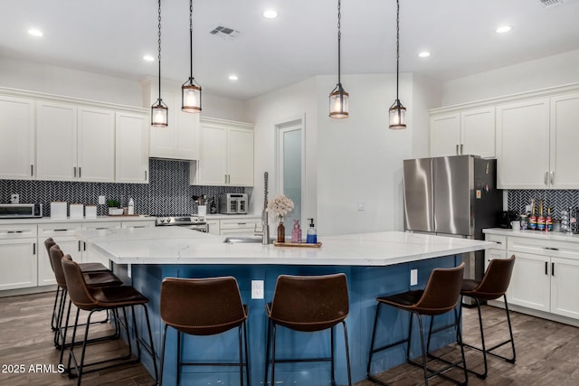 kitchen with white cabinets, an island with sink, and hanging light fixtures