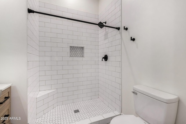 bathroom featuring tiled shower, vanity, and toilet